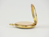 a close up of a gold pocket watch on a white surface