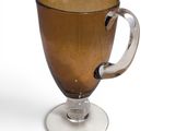 a brown glass cup with a handle on a white plate