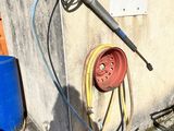 un tuyau fixé au mur, à côté d'un tonneau bleu