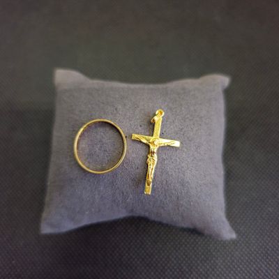 une bague en or et une croix posées sur un oreiller