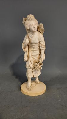figurine en ivoire sculpté représentant une jeune fille avec un panier de fleurs