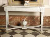 a table with a vase on top of it in front of a painting