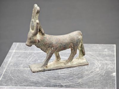une ancienne figurine en bronze représentant un âne, posée sur un socle en marbre