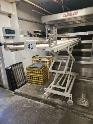 une photo d'un tapis roulant dans un entrepôt, sur lequel se trouvent des caisses de denrées alimentaires