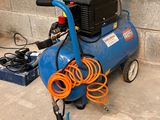 a blue air compressor sitting on the ground next to a brick wall