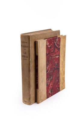 an old book with a red cover sitting on top of a white surface