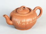 une théière marron avec une inscription, posée sur une table