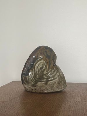 une sculpture en céramique représentant un escargot, posée sur une table en bois