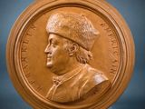 a close up of a bronze medallion with a man wearing a hat