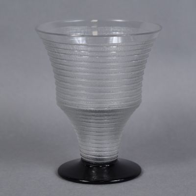 un vase en verre transparent avec un socle noir posé sur une table