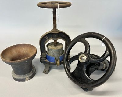 two antique cast iron sewing machines and a wooden bowl on a white surface