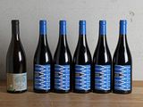 six bouteilles de vin sont alignées sur une table en bois