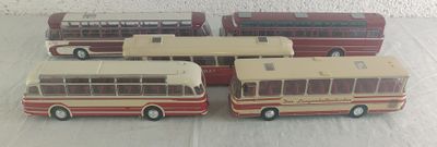quatre petits bus en jouet posés les uns à côté des autres sur une table