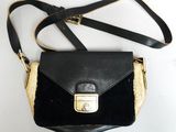 un sac à main noir avec une poignée dorée posé sur une table blanche