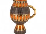 un vase marron et orange avec une anse dorée sur fond blanc