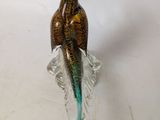 a glass sculpture of a bird sitting on a leaf