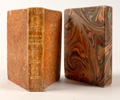 un vieux livre posé sur un bloc de bois, à côté d'un livre plus petit