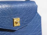 the back of a blue purse with a gold lock on it