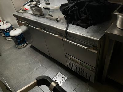 plan de travail en acier inoxydable dans une cuisine commerciale avec des casseroles et des poêles dessus