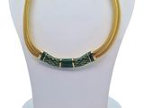 a green and gold necklace and earrings set on a mannequin