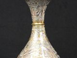 a silver vase that is sitting on a black surface