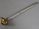an antique silver spoon with a handle on a gray surface