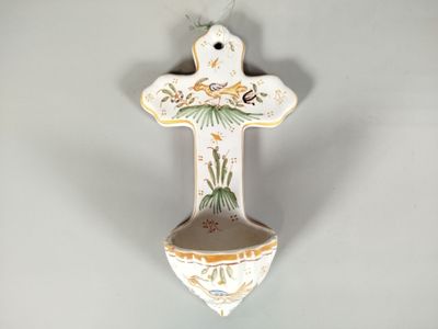 une croix en céramique accrochée au mur, sur laquelle est représenté un oiseau