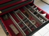 une boîte à outils rouge contenant des outils, posée sur un sol carrelé