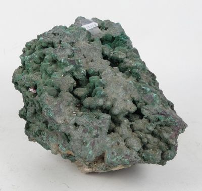 un gros plan d'un morceau de minéral vert sur une surface blanche
