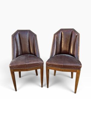 a pair of brown leather chairs with wooden legs