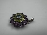 a close up of a purple and green pendant on a white surface