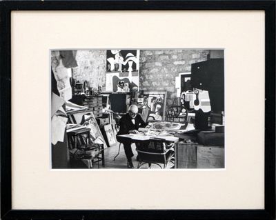 black and white photograph of a man sitting at a desk in an art studio