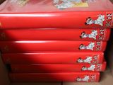 six red books in a cardboard box on top of a table