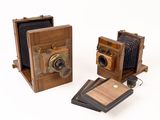 two old cameras are sitting next to each other on a white surface