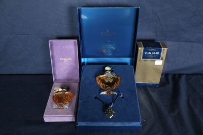 trois flacons de parfum dans un coffret cadeau bleu, posés sur une surface noire