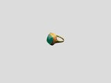 a close up of a gold ring with a green stone on it