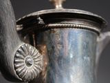 a silver tea pot with a handle on a table