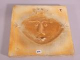 a picture of a ceramic plaque with a face on it