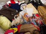 a pile of purses and handbags sitting on a bed