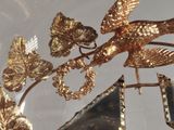 a gold bird on a branch with a mirror in the background
