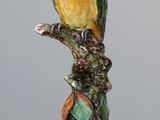 a figurine of a parrot perched on a tree branch