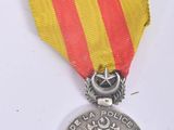an old medal with a red and yellow ribbon on a white surface