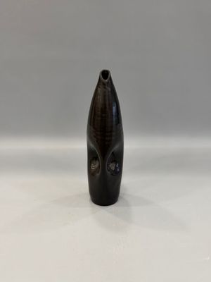 un vase noir posé sur une table blanche