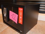a black microwave with a pink sticker on the door