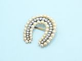 a close up of a brooch with pearls on a blue background