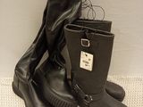 une paire de bottes en cuir noir à semelles en caoutchouc posées sur une surface blanche