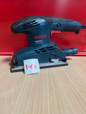 une ponceuse orbitale Bosch posée sur une table, à côté d'une boîte rouge