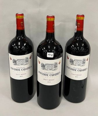 trois bouteilles de vin rouge sont alignées sur une surface blanche