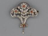 a close up of a brooch with a pearl and a flower