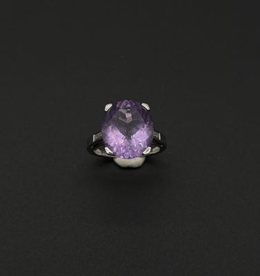 un gros plan d'une bague ornée d'une pierre violette sur un fond noir